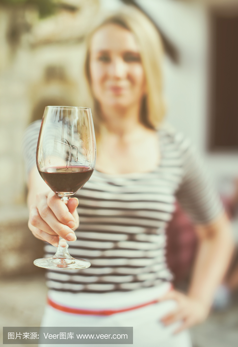一個(gè)女人在室外遞上一杯紅酒。復(fù)古的效果。
